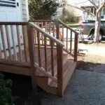 Newly built hardwood deck landing with matching railing and steps at a shingled cottage
