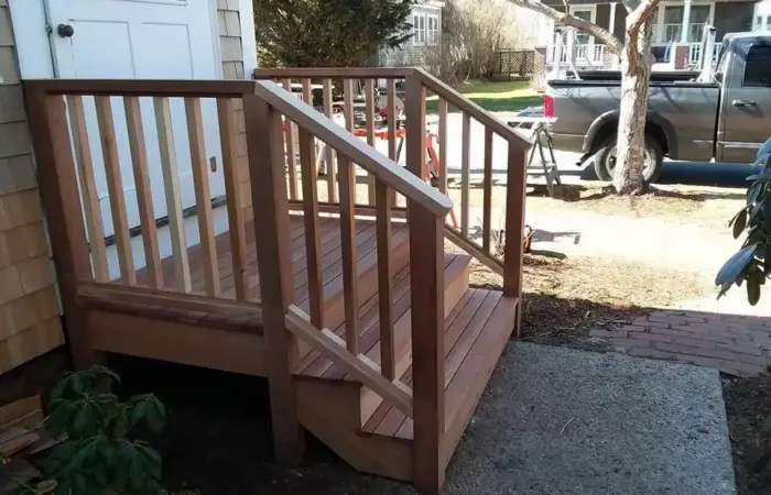 Newly built hardwood deck landing with matching railing and steps at a shingled cottage