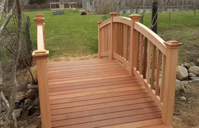 A custom-built wooden bridge with cedar railings in a Nantucket backyard. Build by R. Bradley builders of Nantucket.