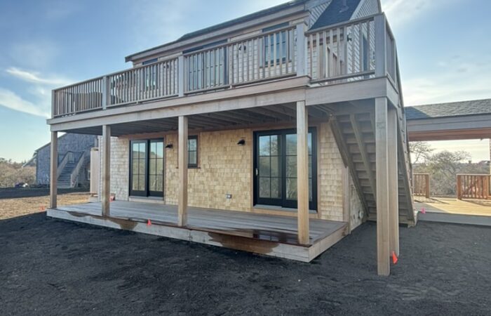 New shingled structure at Lyons Lane with an upper deck, turned railing, and exterior stair
