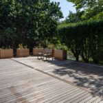 Wide hardwood deck framed by custom cedar planter boxes and a clipped privet hedge