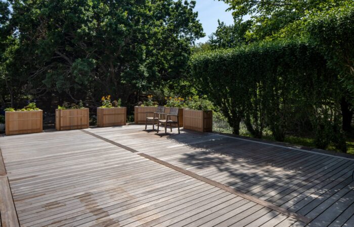 Wide hardwood deck framed by custom cedar planter boxes and a clipped privet hedge