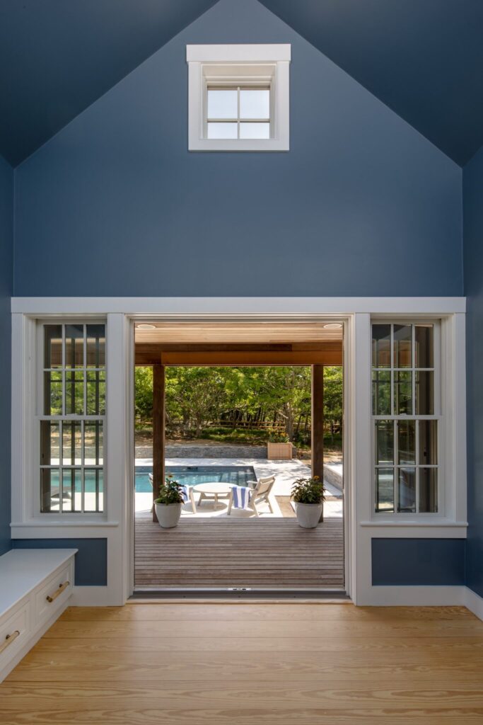 Pool house with slate blue walls, a built-in window bench, and doors opening to the pool deck