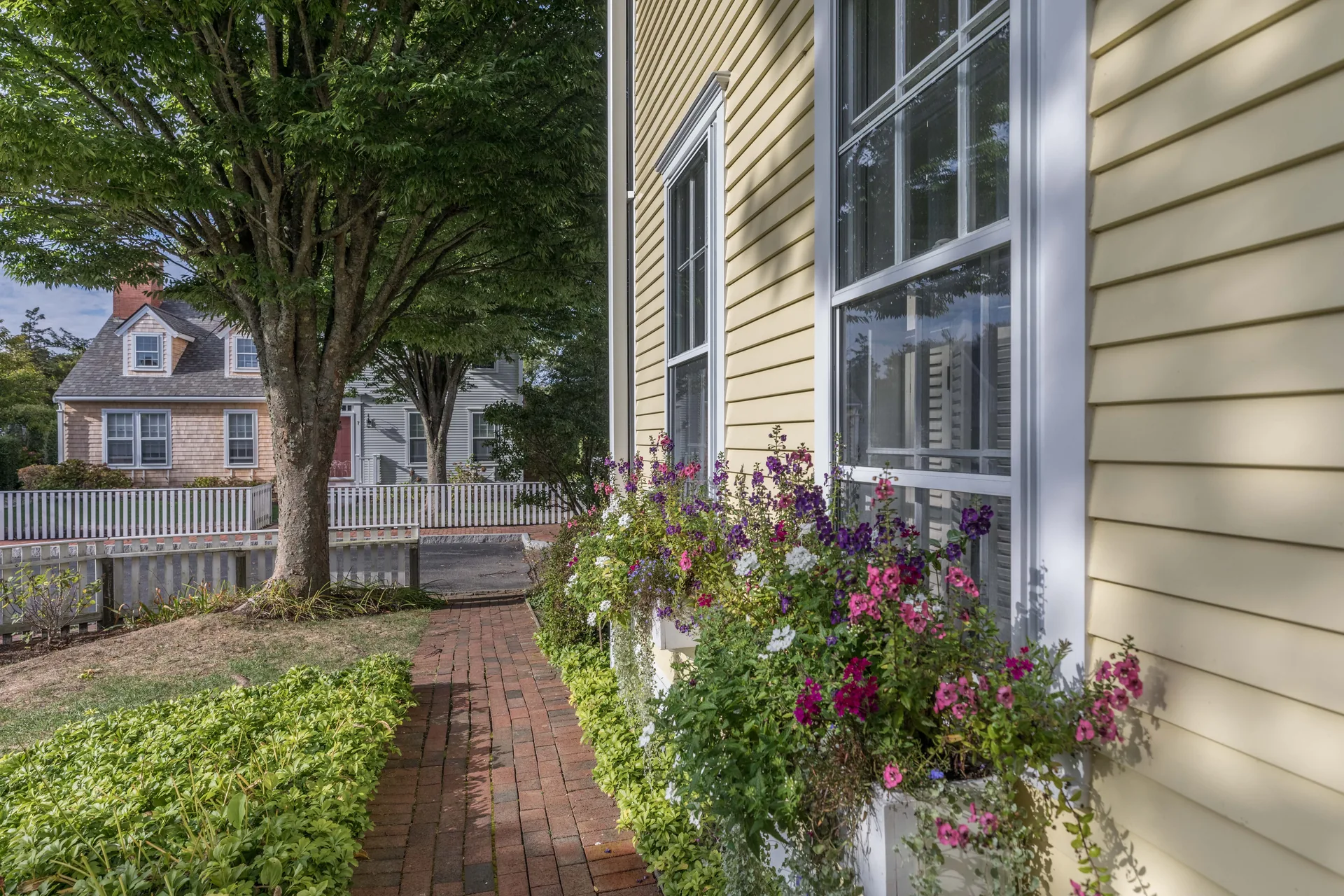 Side exterior view with window flower boxes and brick walkway