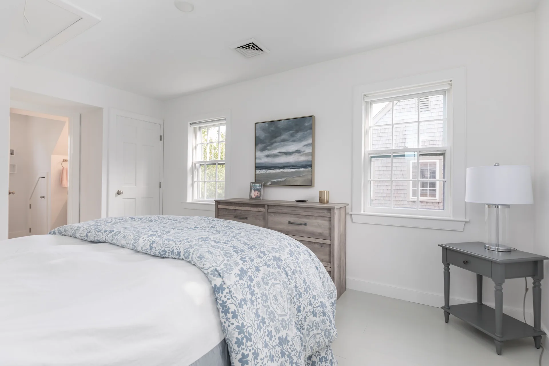 Guest bedroom with blue floral duvet and seascape art