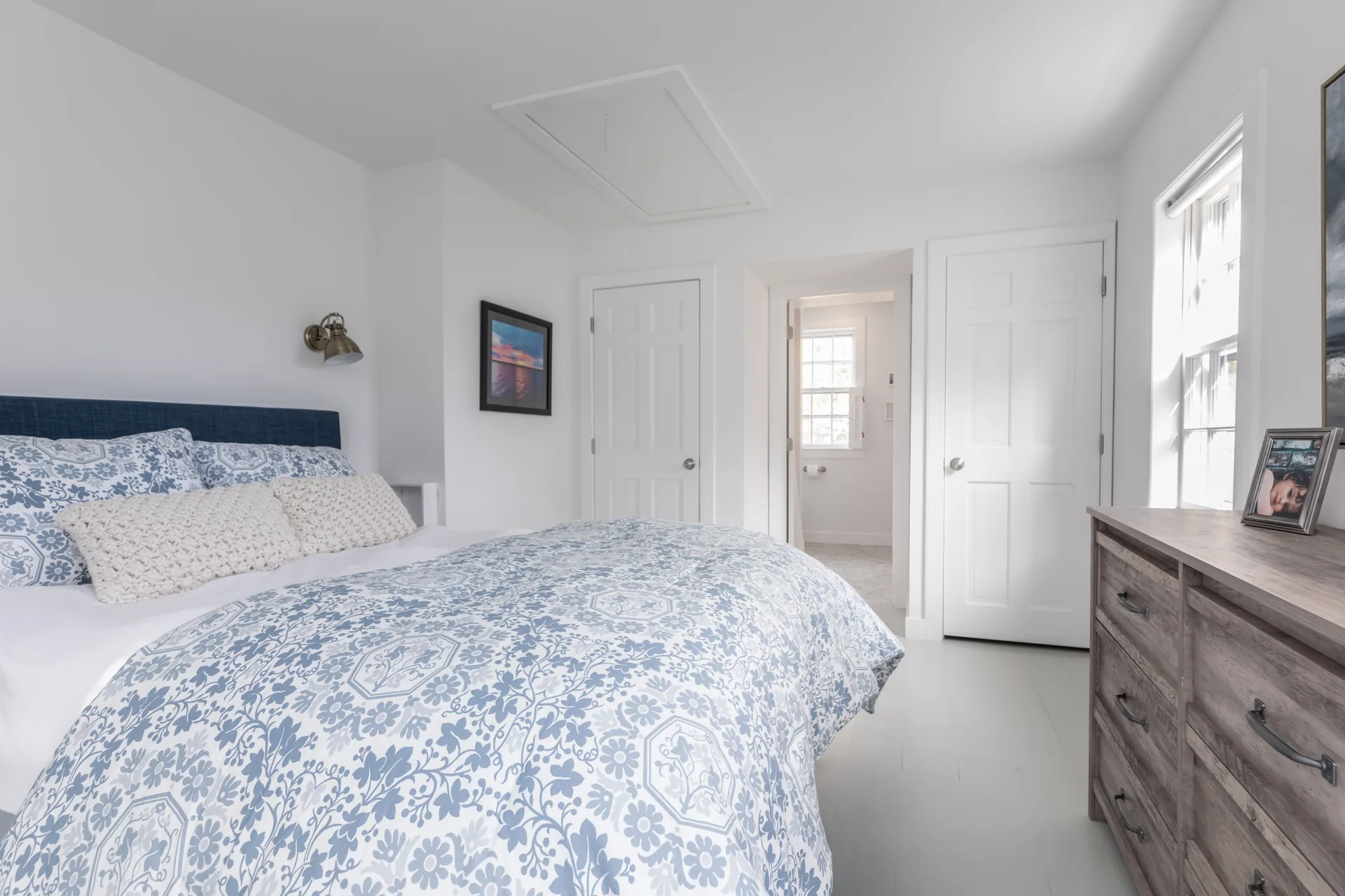 Guest bedroom with navy headboard and sunset artwork