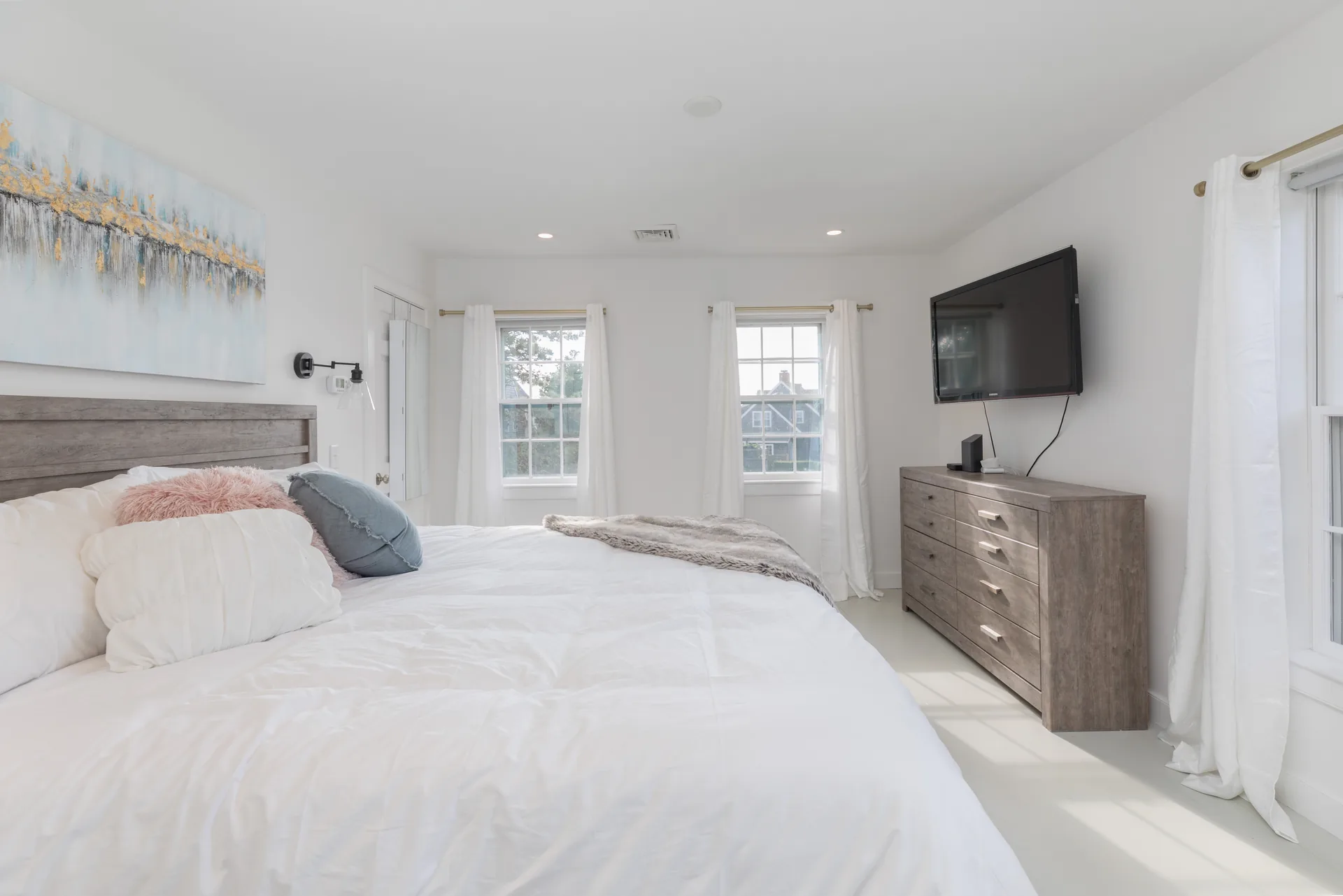 Master bedroom with wall sconces and white curtains