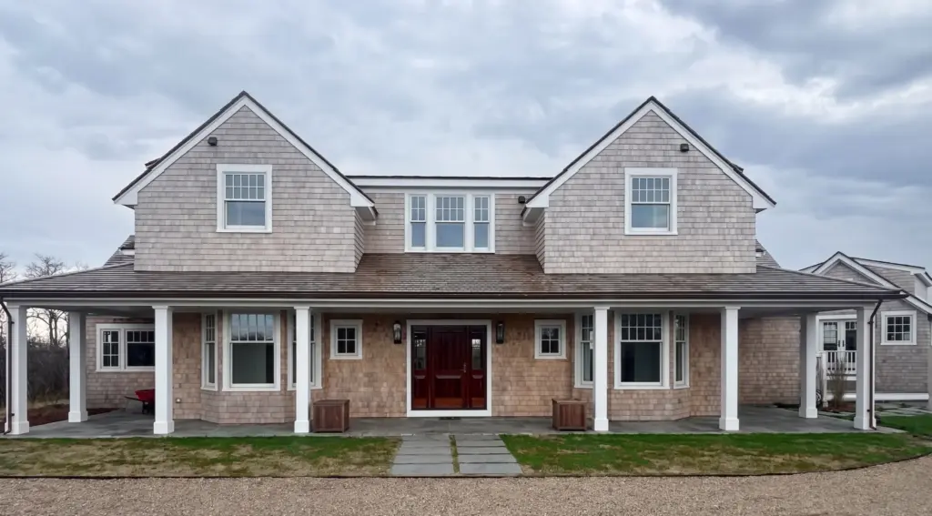Shingled North Pasture Lane home with wraparound porch, twin dormers, and mahogany front door